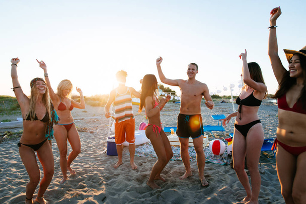 Group of friends making party on the beach at sunset time - 写真・画像