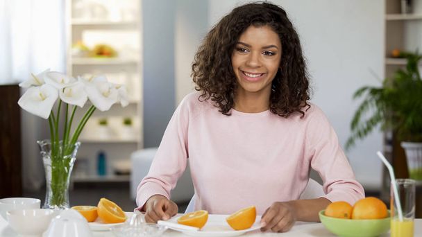 Smiling young woman holding plate with fresh orange, healthy lifestyle nutrition - Foto, Bild