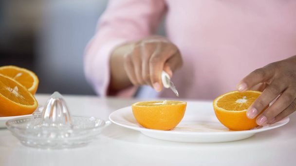 Young lady cutting orange with knife on plate, cooking fresh juice in morning - Фото, изображение