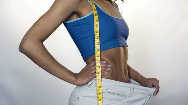 Slim woman pulling waist of big trousers away, showing weight loss, workout - Φωτογραφία, εικόνα