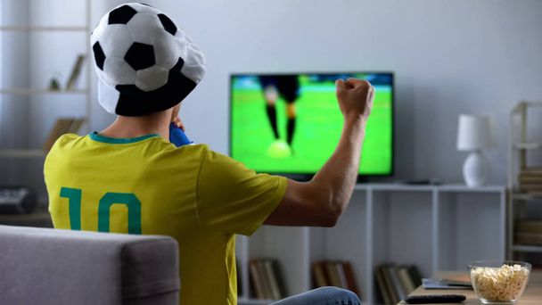 Brazilian fan actively cheering favourite football team watching match on tv - Foto, Imagem