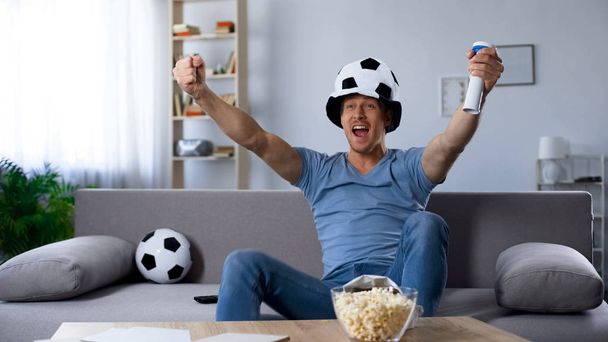Ardent football supporter in fan hat rejoicing to scored penalty kick, victory - Фото, изображение