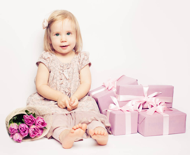 schöne Kind Mädchen mit Blumen und rosa Geschenkbox, Geburtstag Hintergrund - Foto, Bild