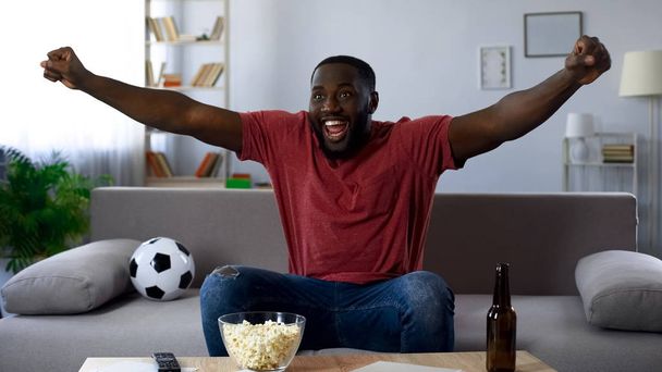 Afro-american man watching sports competition, happy fan victoriously screaming - Photo, Image