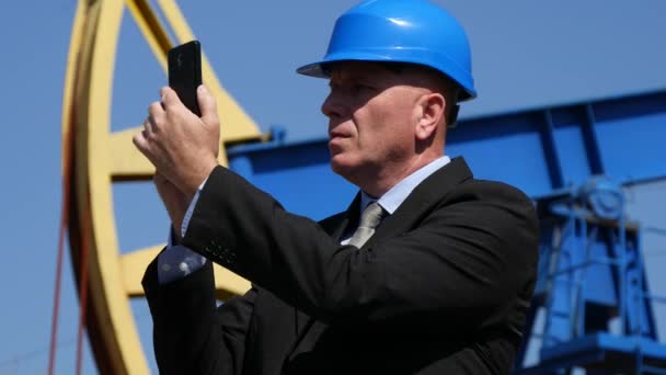 Oil Company Manager Shooting Images with Cell in Oil Pump Extraction Field - Filmati, video
