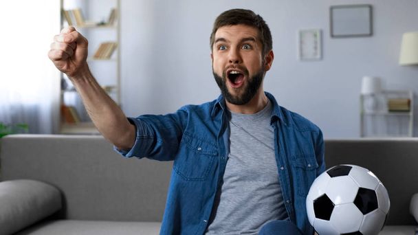Cheerful guy loudly screaming watching football match, successful game result - Fotó, kép