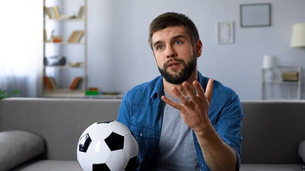 Young man nervously watching football match on tv home, frustrated at team loss - Фото, изображение