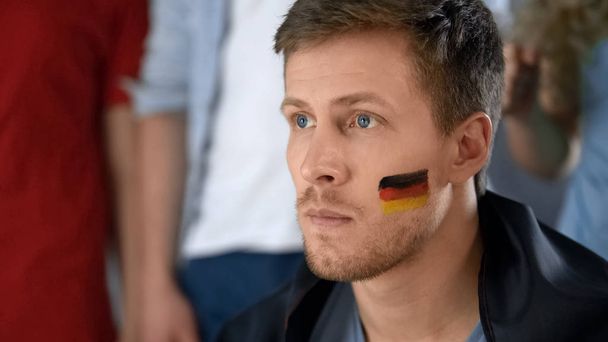 Upset German football fan disappointed with defeat, watching game with friends - Фото, изображение