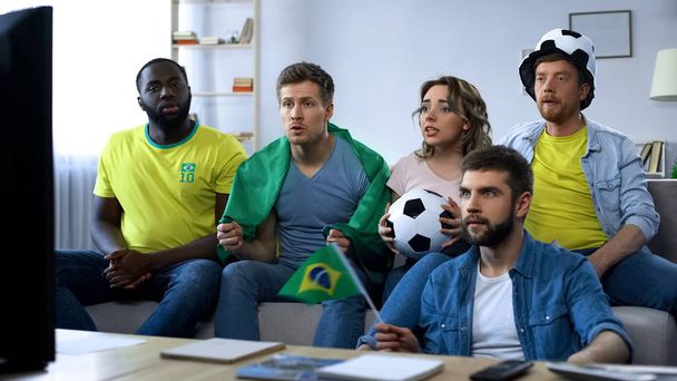 Brazilian group of friends watching football game on tv at home, togetherness - 写真・画像