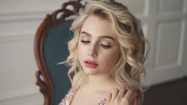 evening makeup and hair. portrait of a girl in an evening dress. blonde with blue eyes posing for the camera - Footage, Video