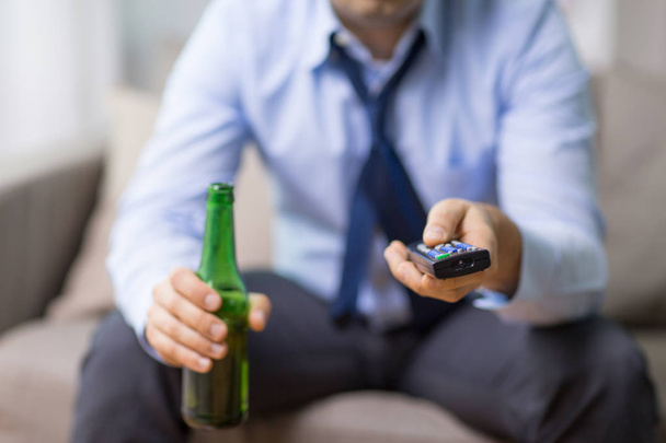 close up of man with tv remote drinking beer - Фото, изображение