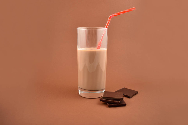Chocolate milk stock images. Chocolate milk with chocolate pieces. Glass of chocolate milk on a brown background - Foto, immagini