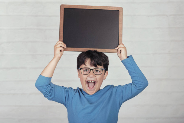 gelukkig kind met een schoolbord op baksteen achtergrond - Foto, afbeelding