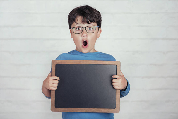 surprised boy with a blackboard on brick background - Foto, immagini