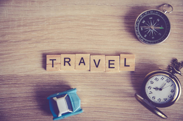 travel concept . travel word on wooden cube block on wood background decoration with compass ,pocket watch and mini car model - Foto, imagen