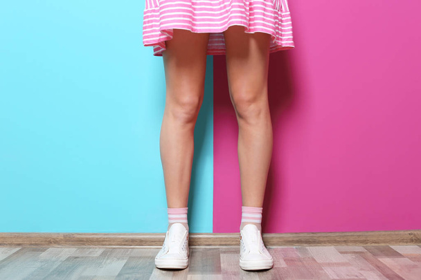 Young woman with sexy legs near color wall - Фото, зображення