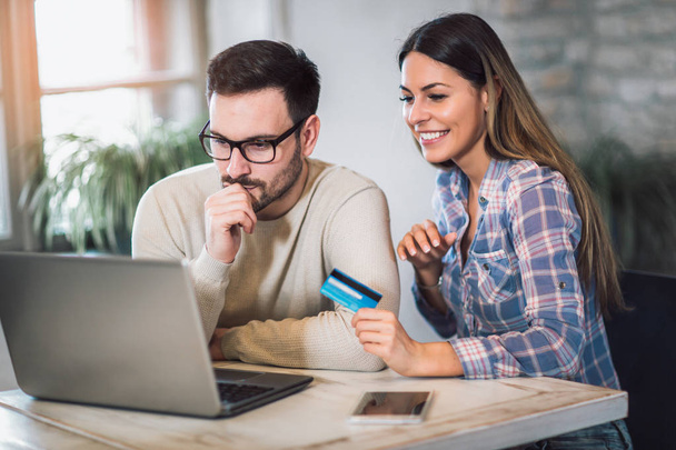 Couple souriant utilisant une tablette numérique et une carte de crédit à la maison
 - Photo, image