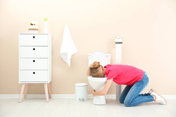 Young woman vomiting in toilet bowl at home - Фото, зображення