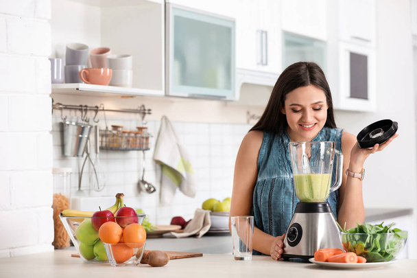 Young woman preparing tasty healthy smoothie at table in kitchen - 写真・画像