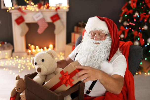 Authentic Santa Claus holding wooden crate with gifts indoors - 写真・画像