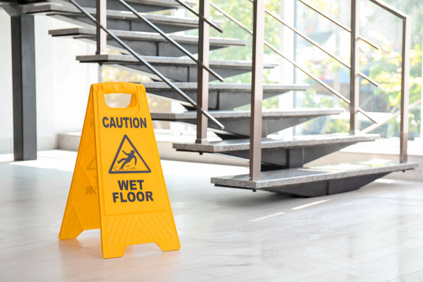 Safety sign with phrase Caution wet floor near stairs. Cleaning service - Valokuva, kuva