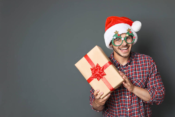 Young man with Christmas gift on grey background - Valokuva, kuva