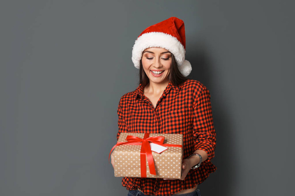 Young woman with Christmas gift on grey background - Фото, зображення