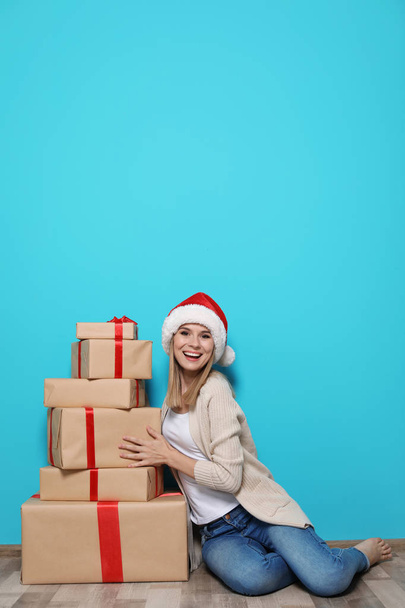 Young woman with Christmas gifts near color wall - Foto, Bild