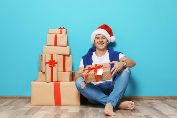 Young man with Christmas gifts near color wall - Foto, immagini