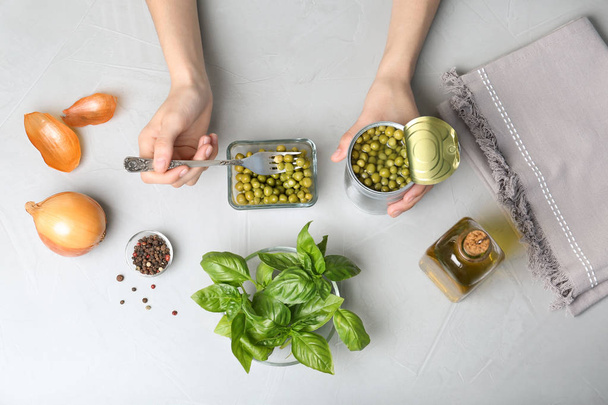 Woman with canned green peas at table, top view - Foto, Imagen