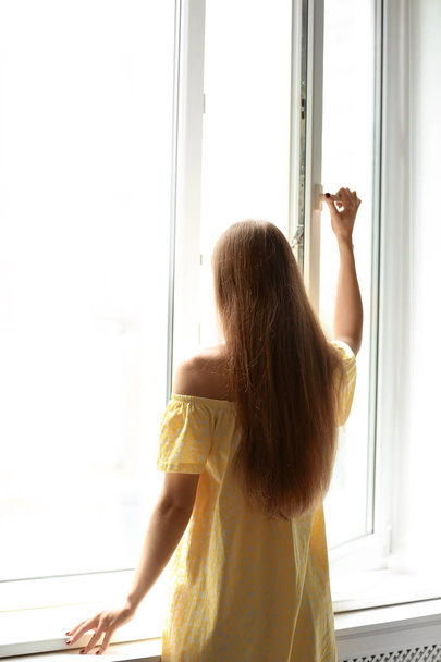 Young beautiful woman opening big window in room - Fotó, kép