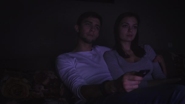 Couple watching television program in dark room - Materiał filmowy, wideo