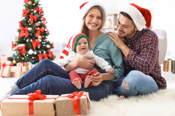 Happy couple with baby celebrating Christmas together at home - Photo, image