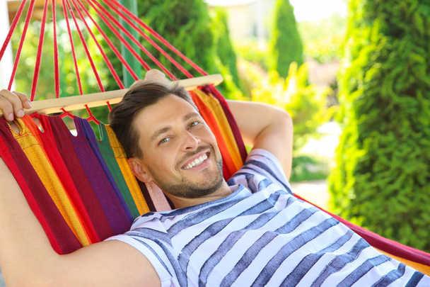 Man relaxing in hammock outdoors on warm summer day - Фото, изображение