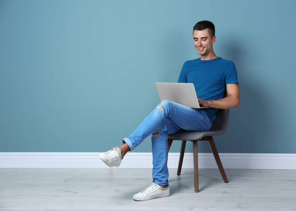 Man in casual clothes with laptop near color wall - Foto, imagen