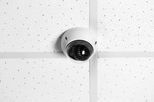 Modern security CCTV camera on ceiling indoors - Foto, Bild