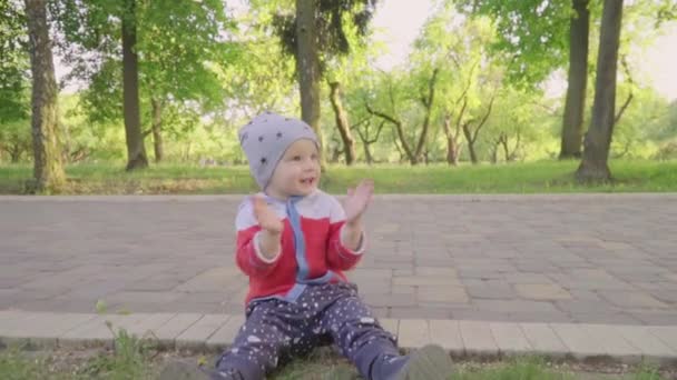 Çok güzel yürümeye başlayan çocuk, çiçek açan ağaçlar ile sunset Bulvarında bir yolda oynayan çocuk - Video, Çekim
