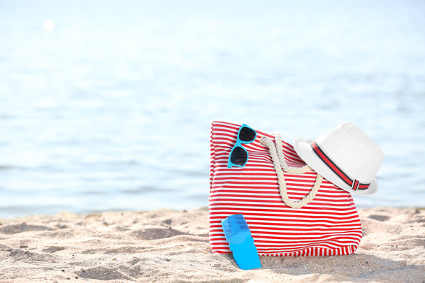 Bag, sunglasses and hat on sand near sea. Beach object - Zdjęcie, obraz