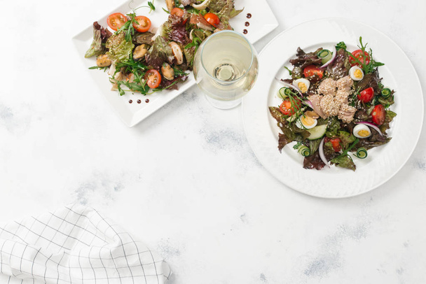 Vista superior de dois tipos de saladas servidas com vinho branco
 - Foto, Imagem
