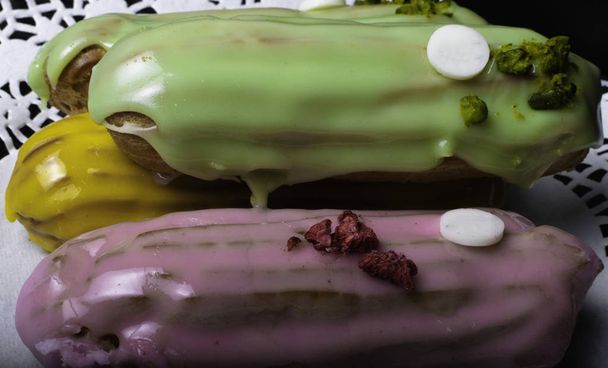 French traditional eclair, decorated with raspberry and cream on the dark wood table - Photo, Image
