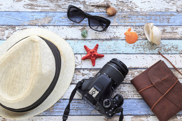 Concepto de verano con sombrero, cámara, gafas de sol, diario y conchas vista superior
 - Foto, imagen