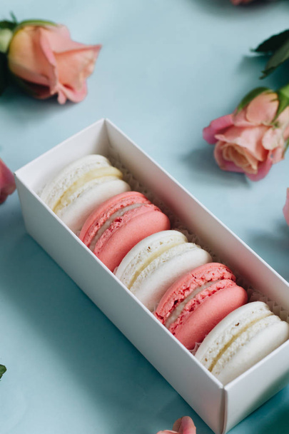 composition of delicious macaroons and pink roses on blue table - Fotografie, Obrázek