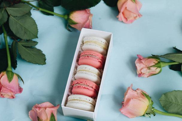 composition of delicious macaroons and pink roses on blue table - Foto, immagini
