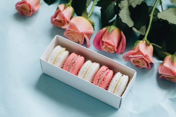composition of delicious macaroons and pink roses on blue table - Foto, Imagen