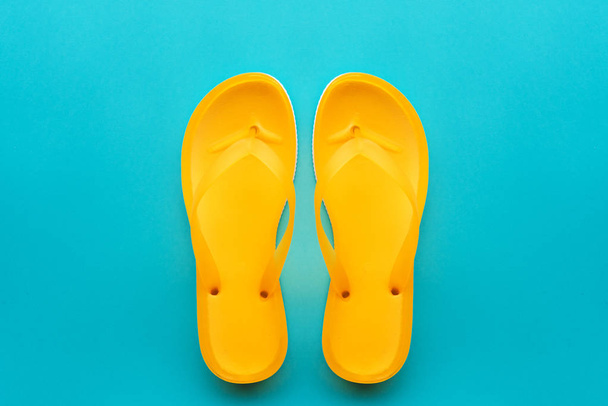 Yellow flip flops on blue background, top view flat lay minimal composition - Fotoğraf, Görsel