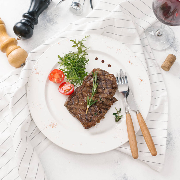 Top view of beefsteak served with arugula and rosemary twig on white plate - Fotoğraf, Görsel