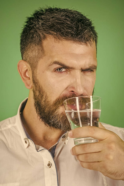 man with beard on serious face drink water from glass - Фото, зображення