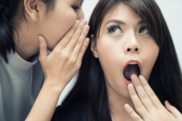Dwa Azji kobieta plotek odsłaniając tajemnicę jej przyjaciel w biurze. Koncepcja komunikacji i przyjaźni ludzie - Zdjęcie, obraz
