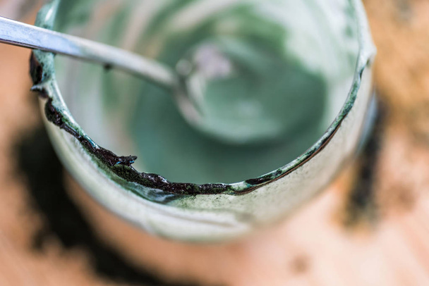 Genel gider closeup görünümü mutfak masasının üzerinde yeşil spirulina tozu ile karışık taze kefir probiotik içki kaşık ile cam boşalttı - Fotoğraf, Görsel