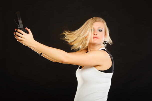 Music, passion concept. Studio shot of blonde young woman holding big headphones having windblown hair. - Foto, afbeelding
